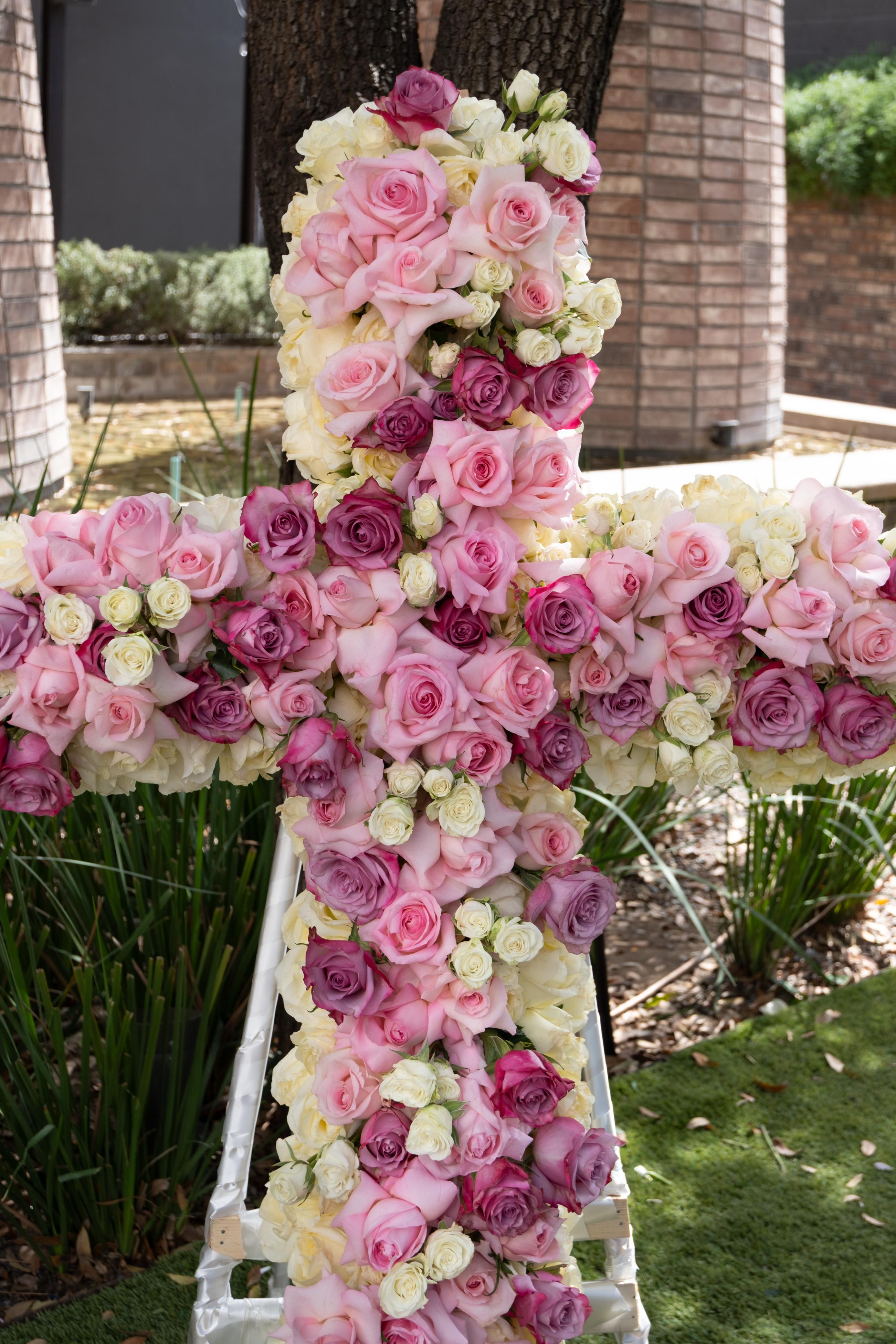 Rocío, cruz en tonos rosas y lilas.