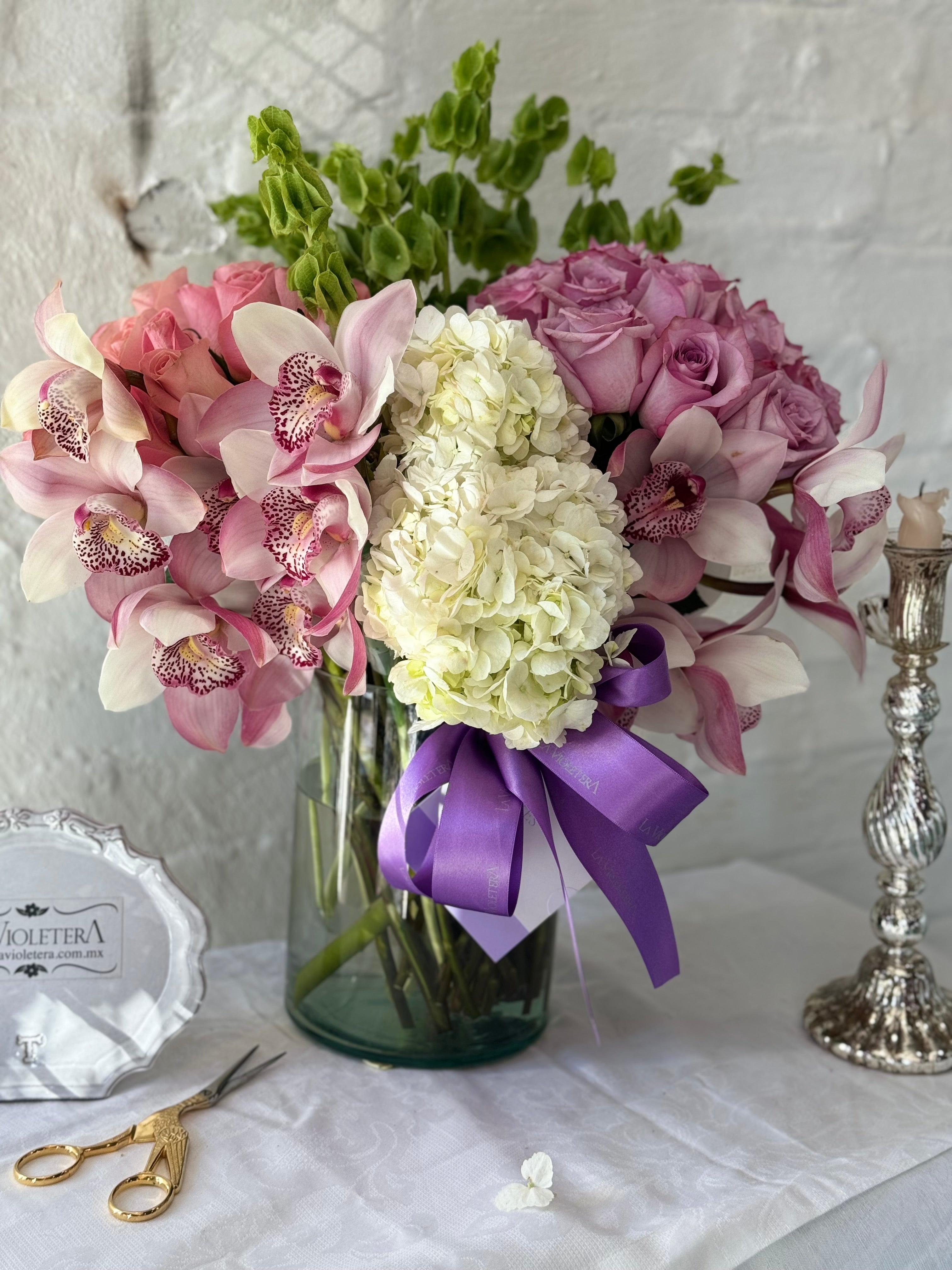 Clara, arreglo floral con 2 buckets de rosas y rodeado de orquídeas .