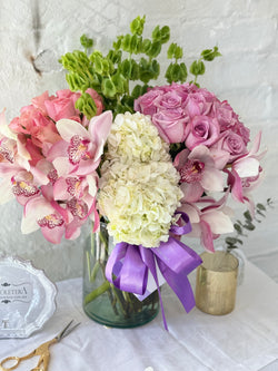 Clara, arreglo floral con 2 buckets de rosas y rodeado de orquídeas .