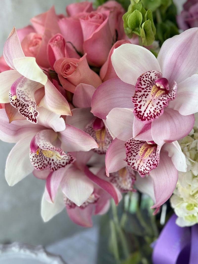 Clara, arreglo floral con 2 buckets de rosas y rodeado de orquídeas .