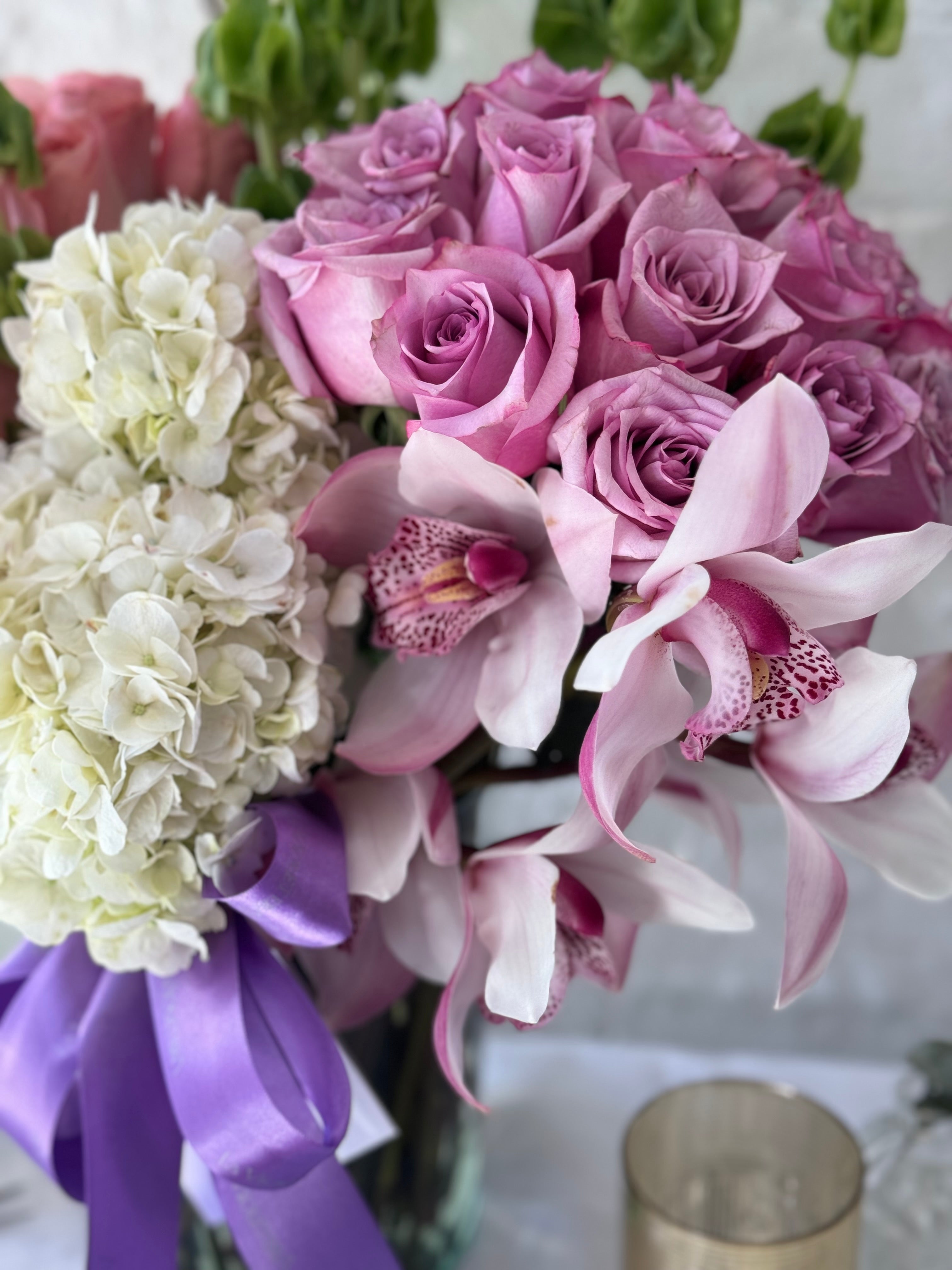 Clara, arreglo floral con 2 buckets de rosas y rodeado de orquídeas .