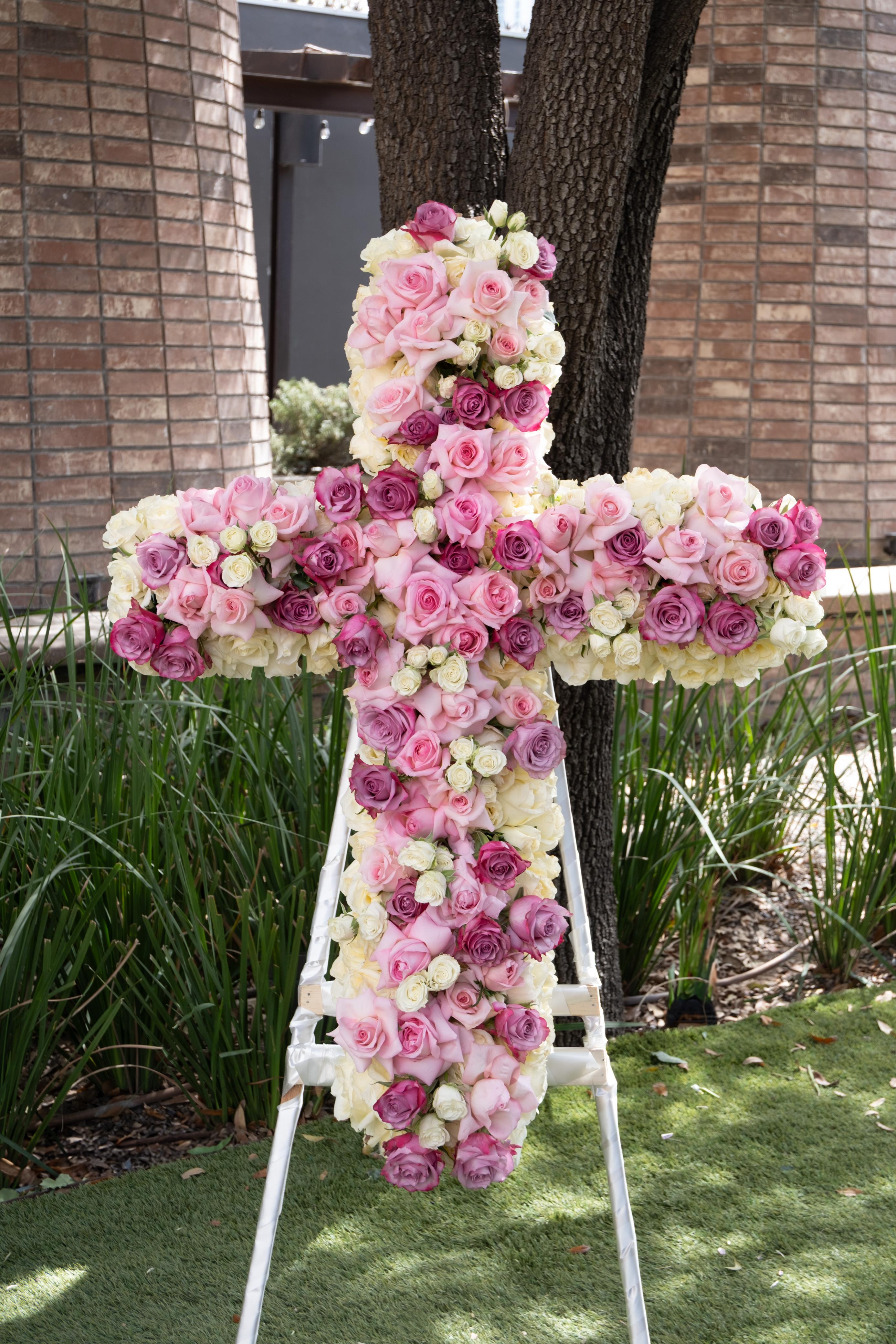Rocío, cruz en tonos rosas y lilas.
