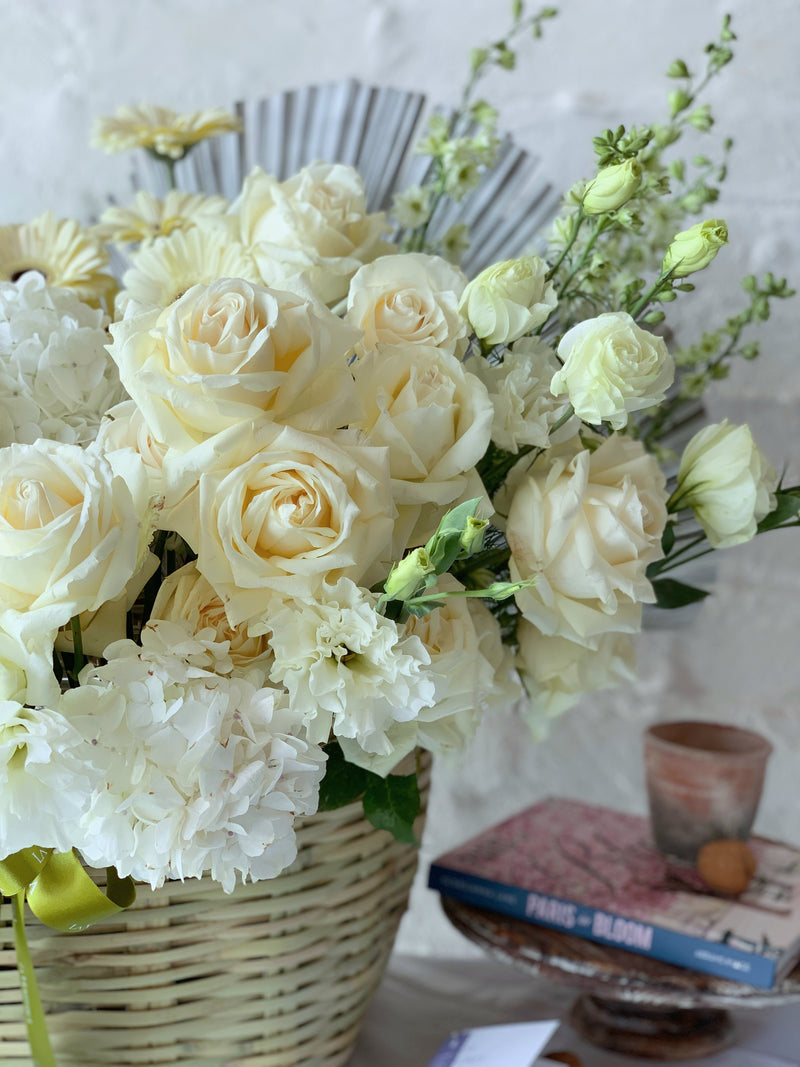 Mara, arreglo floral en canasta en tonos blancos.
